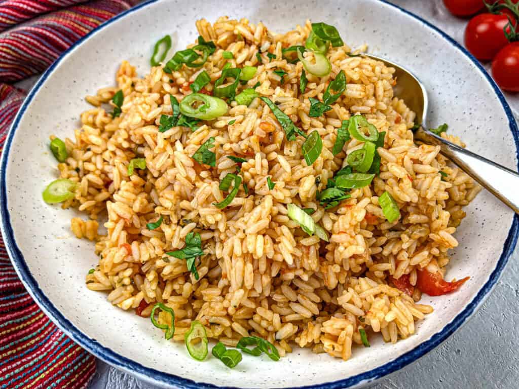 Mexican rice on a white plate with a blue design.