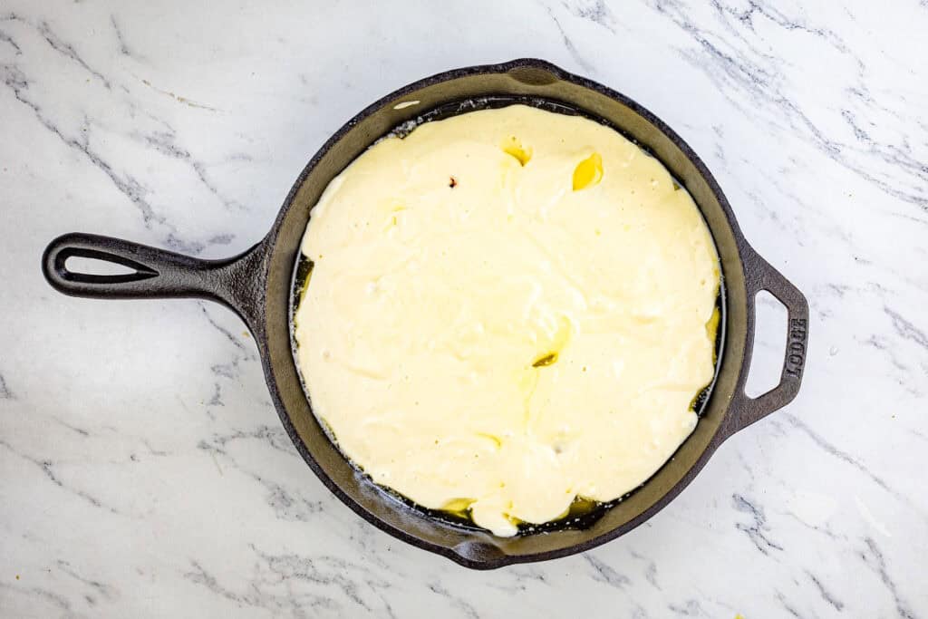 Pour the batter over the fruit in the cake pan.