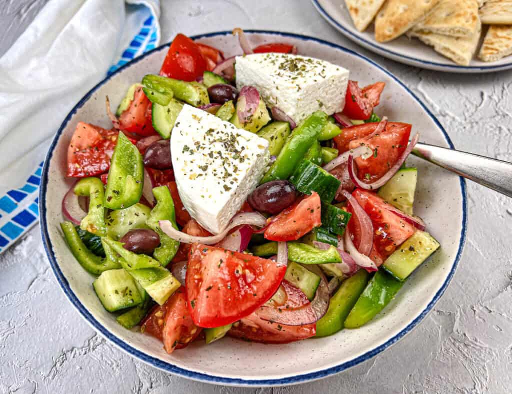 A bowl of Horiatiki Salad with feta cheese on top.