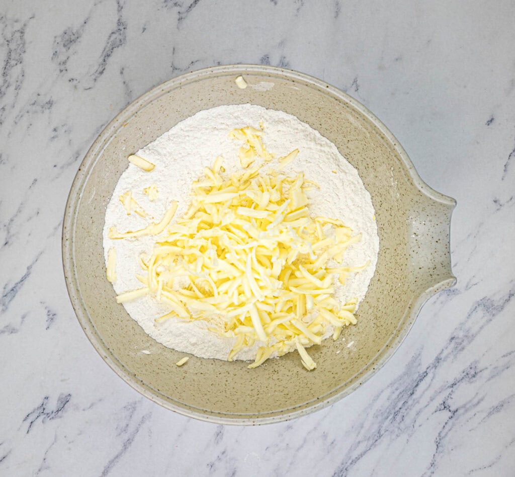 Grate butter with a coarse cheese grater and stir into the flour mixture.