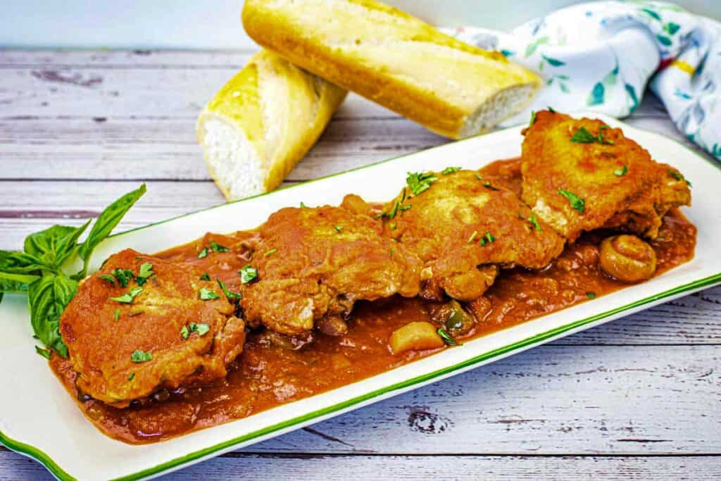 Four pieces of Chicken Cacciatore on a serving platter.