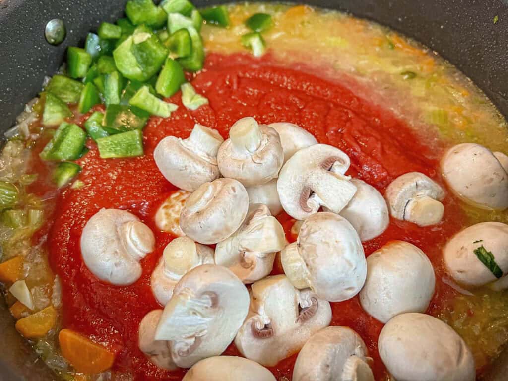 Add the tomatoes, chicken broth, rosemary, mushrooms, bell pepper, and capers to the skillet