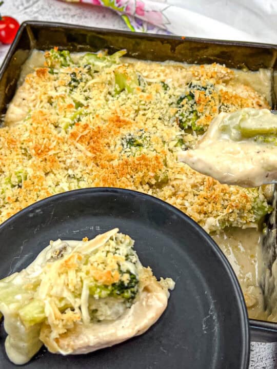 A spoon and a small plate with a portion of Chicken Divan.