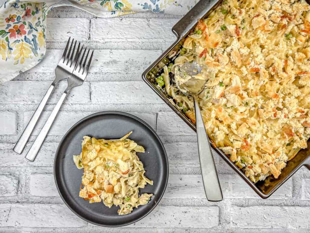 Top-down Classic Tuna Noodle Casserole with a small portion on a black plate.