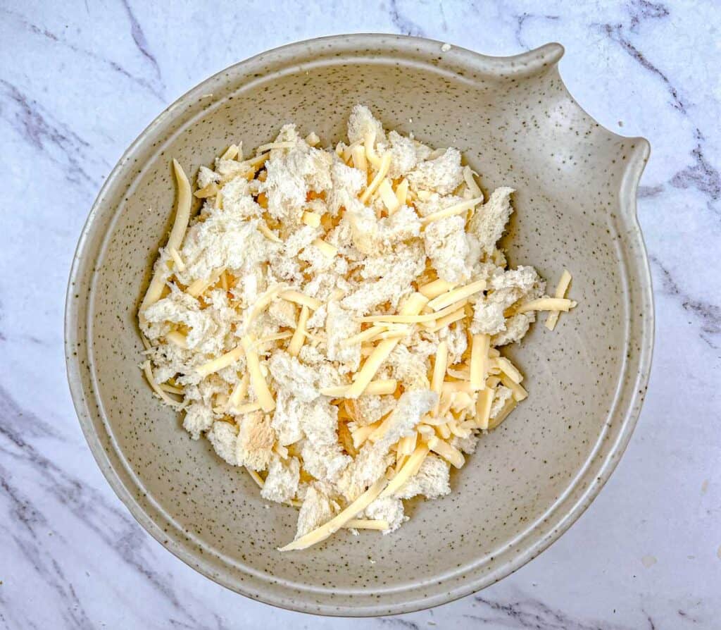 Tear bread into pieces and add to a bowl with shredded cheese.