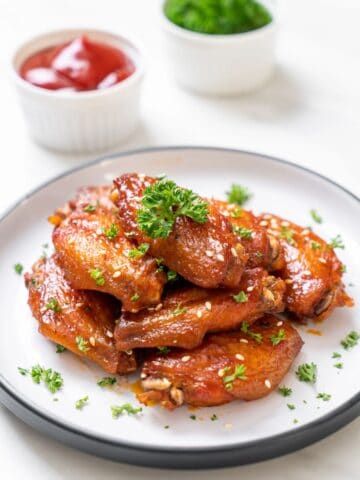 Baked barbecue chicken wings with white sesame on a plate.