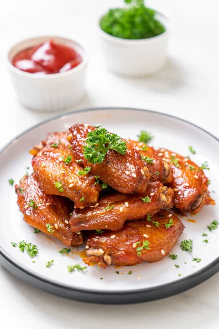 Baked barbecue chicken wings with white sesame on a plate.