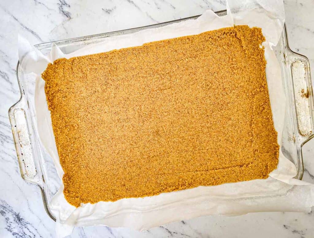 Press firmly into the bottom of the prepared baking dish in an even layer.