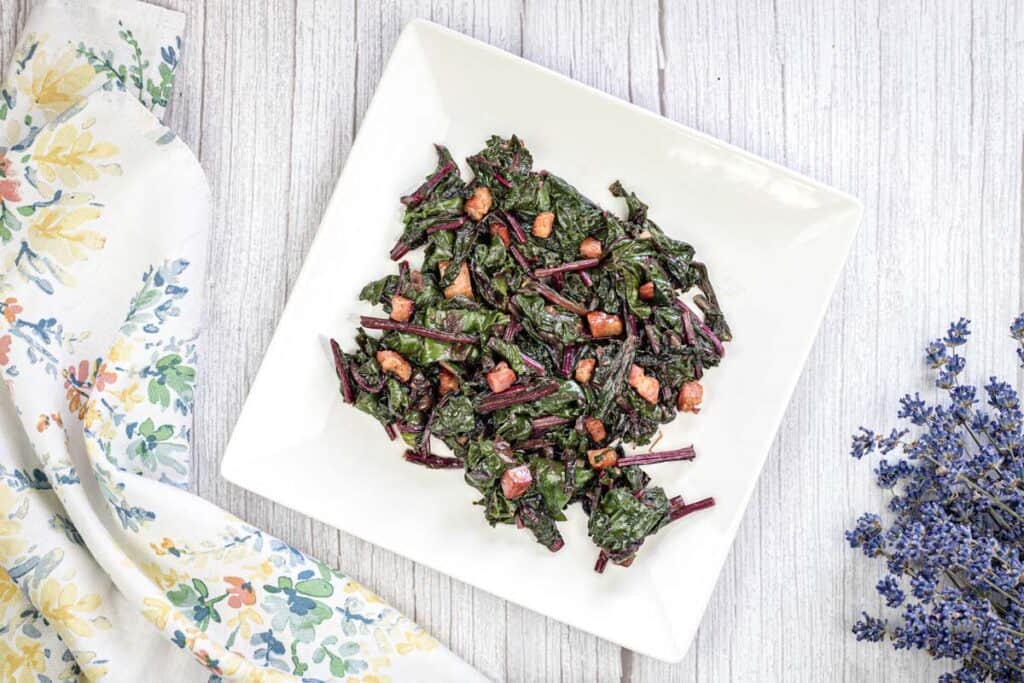 Top-down shot of Sauteed Beet Greens with Pancetta on a white plate.