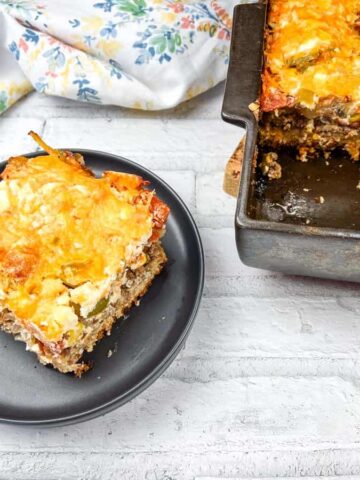 A portion of John Wayne Casserole on a black plate beside the pan.