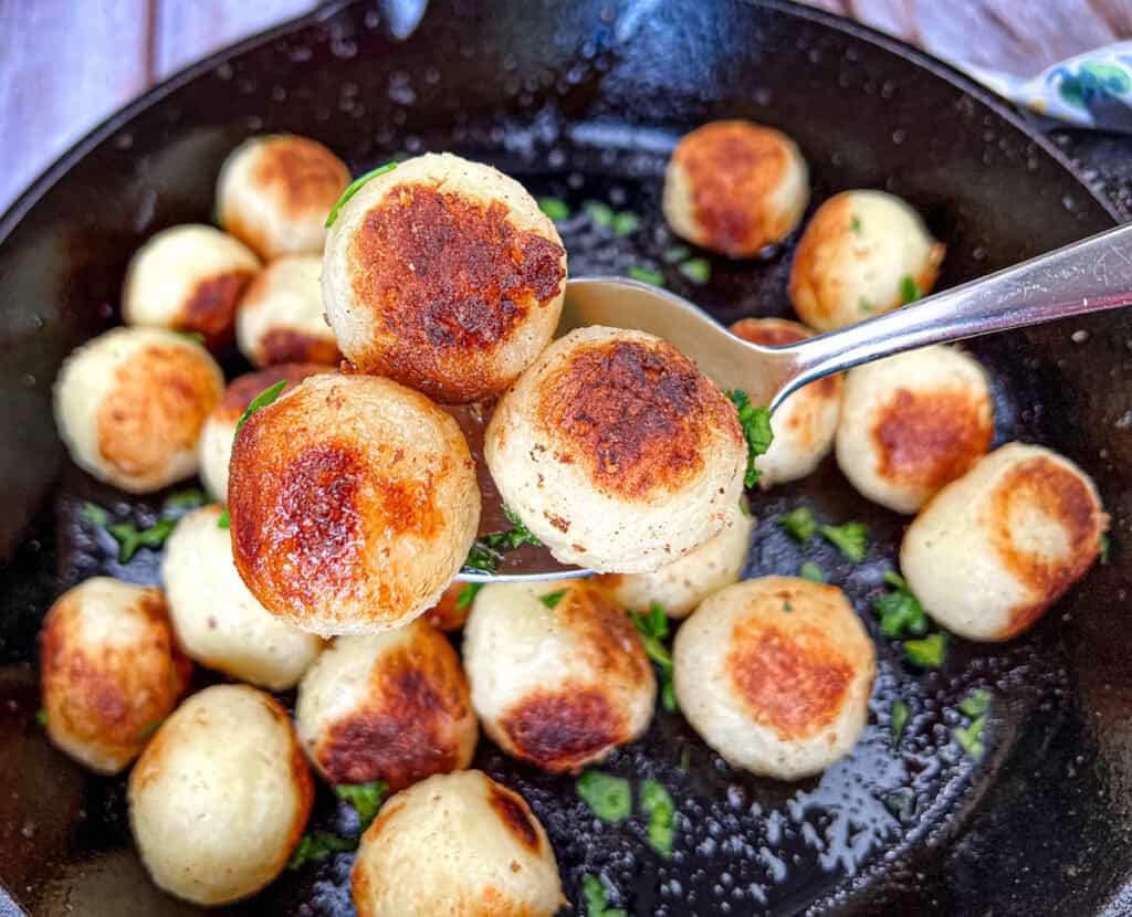 A spoon with three pieces of Parisian potatoes.