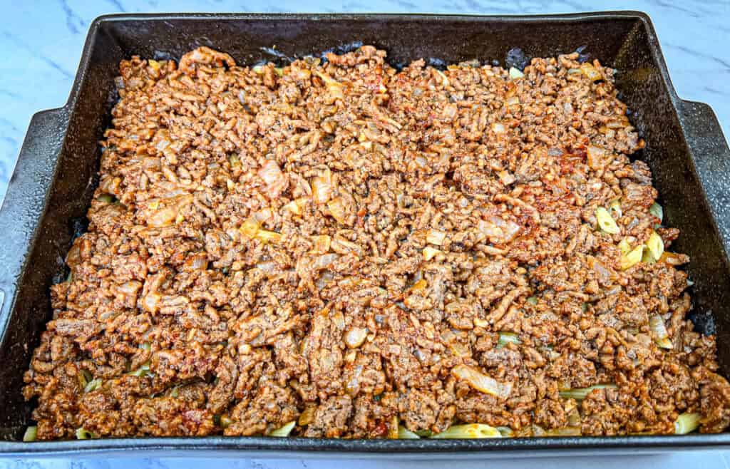 Spread the ground beef mixture evenly over the pasta.