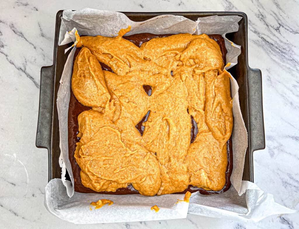 Layer pumpkin and brownie batters into the 9×9 pan.