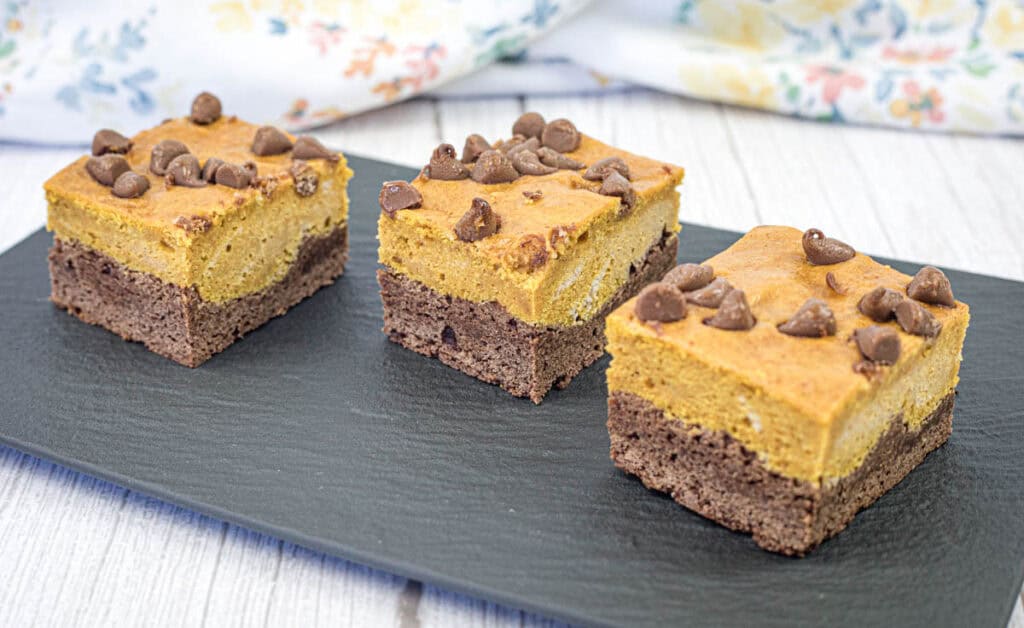 Three pieces of pumpkin brownies on a slate plate.