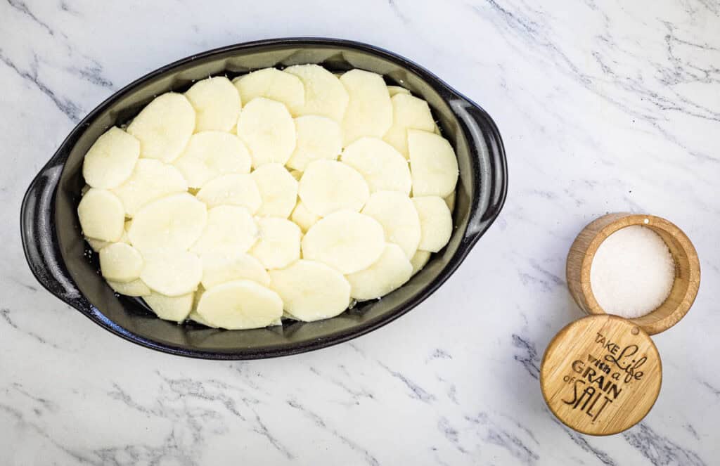 Place potatoes over onions in the casserole dish, then sprinkle with 1/2 teaspoon kosher salt.