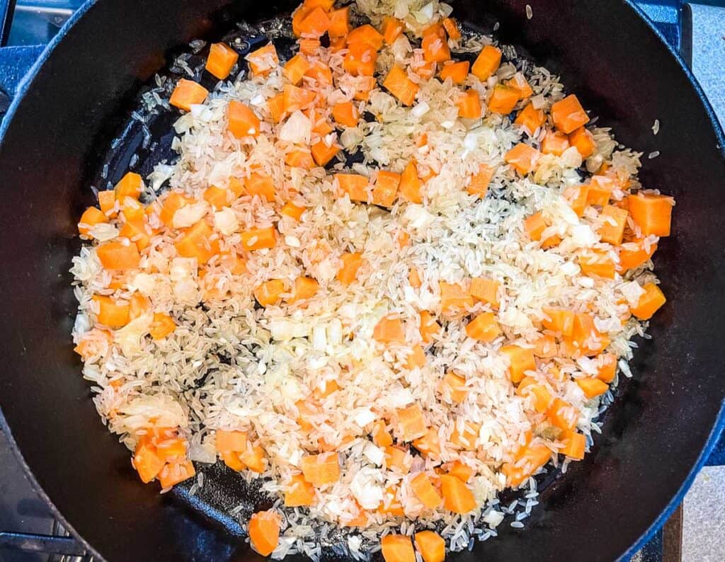 Stir in the minced garlic, raw rice, salt, and black pepper.