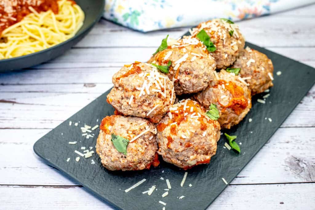 Pieces of classic meatballs on a black slate plate.