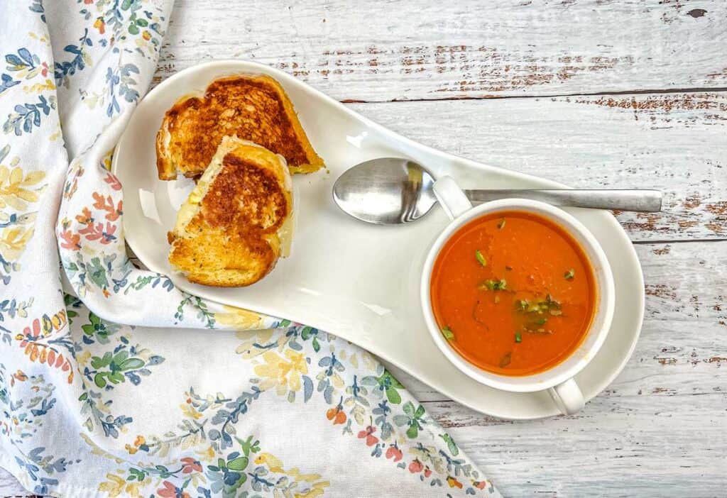 Top-down shot of Old Fashioned Tomato Soup with a bread beside on a plate.