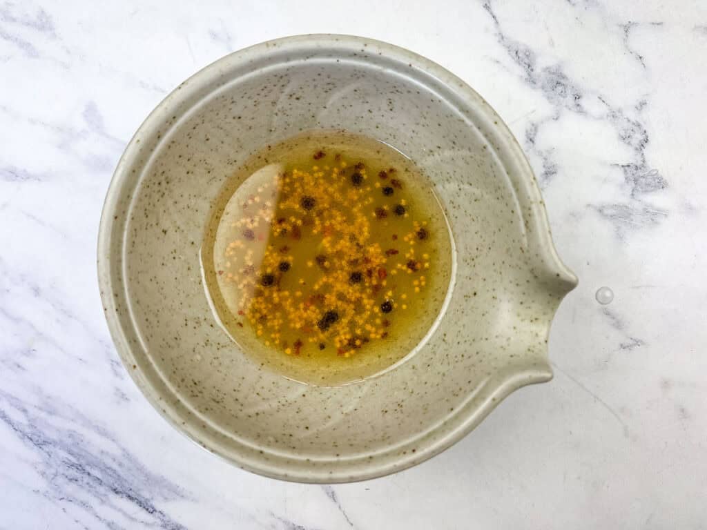 Mix vegetable oil, vinegar, garlic, sugar, mustard seeds, and red pepper flakes in a small bowl.