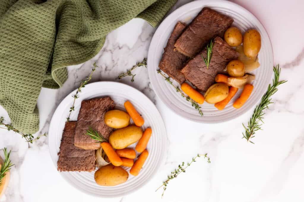 Top-down shot of two plates of Crockpot Slow Cooker Rump Roast.