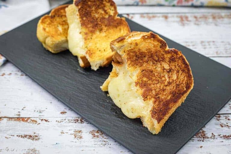 A slate plate with a pieces of The Ultimate Garlic Bread Grilled Cheese.