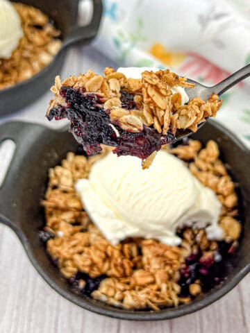 A spoon lifts a portion of Smoked Berry Crisp from a bowl.