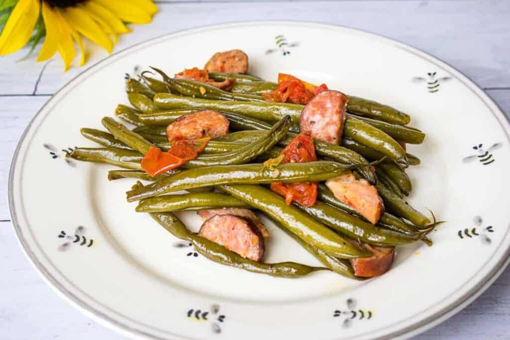 Green beans with pork on a black plate.