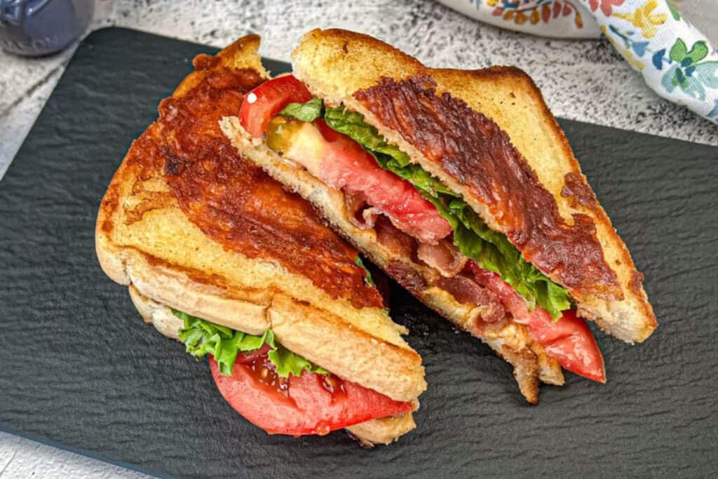 Two Texas BLT on a black slate plate.