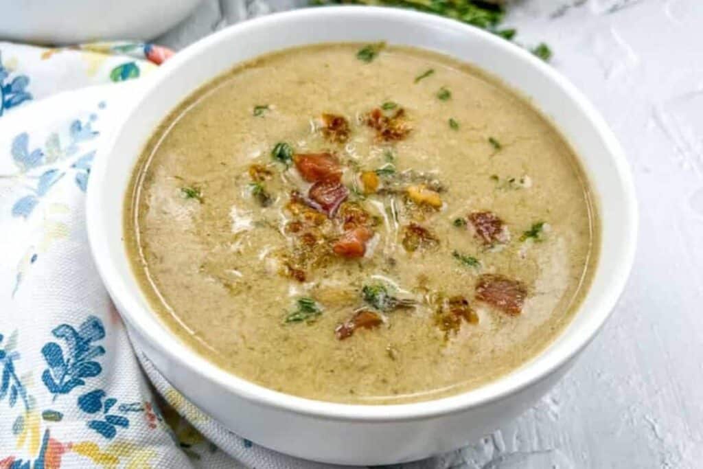 A bowl of caramelized onion & mushroom soup garnished with crispy bits and herbs on top.