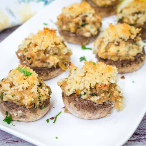 A white plate with pieces of Crab Stuffed Mushrooms.