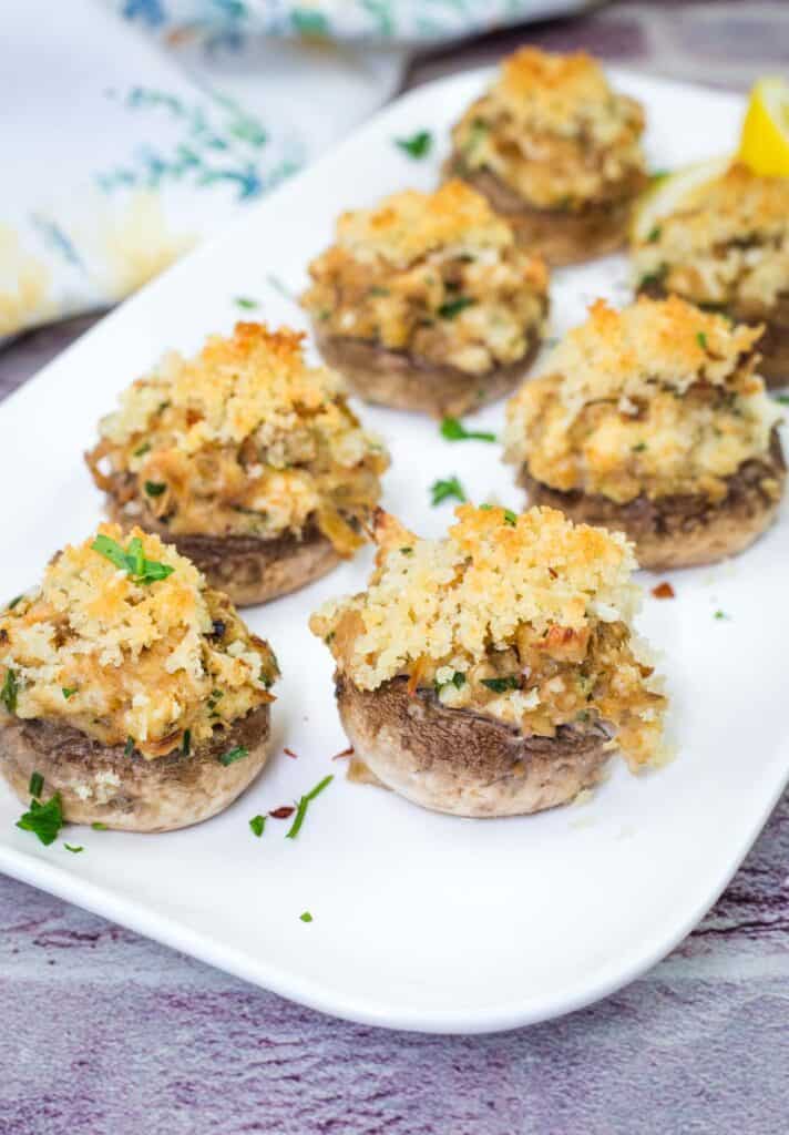 A white plate with pieces of Crab Stuffed Mushrooms.