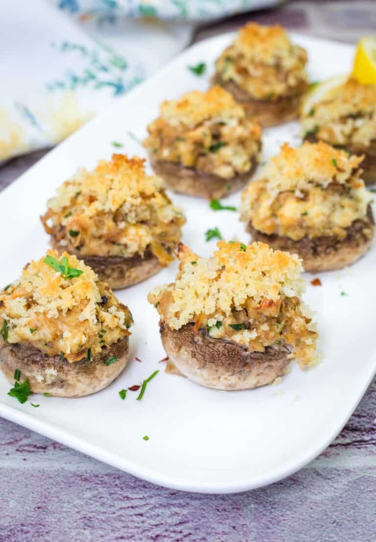 A white plate with pieces of Crab Stuffed Mushrooms.