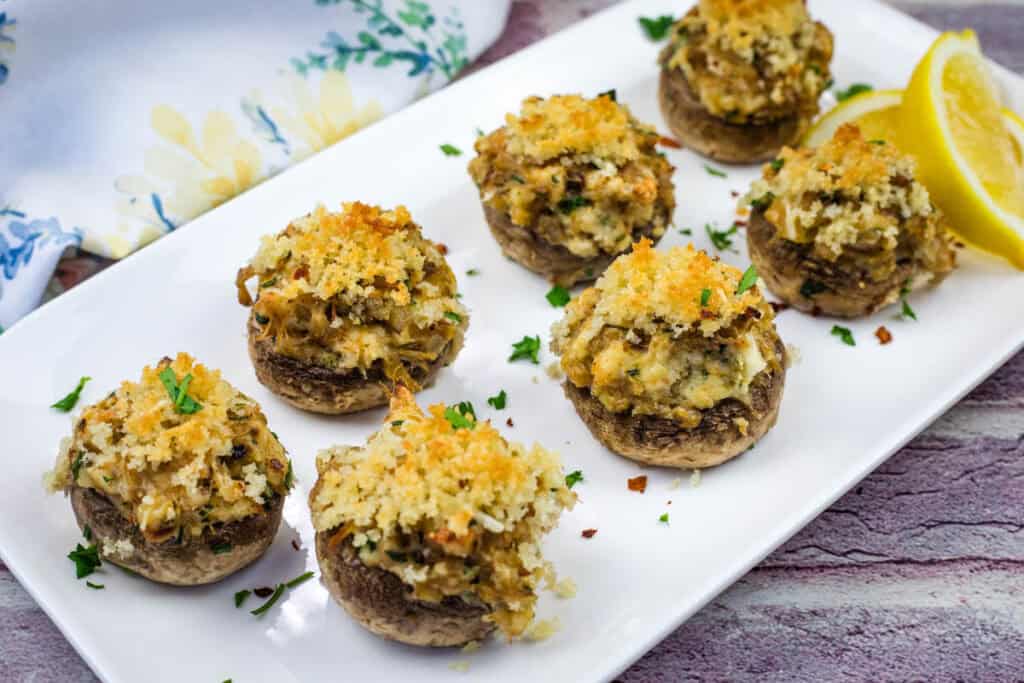 Seven pieces of Crab Stuffed Mushrooms on a white rectangular plate.
