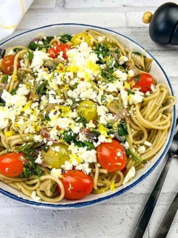 A bowl of pasta with tomatoes, feta and kalamata olives.