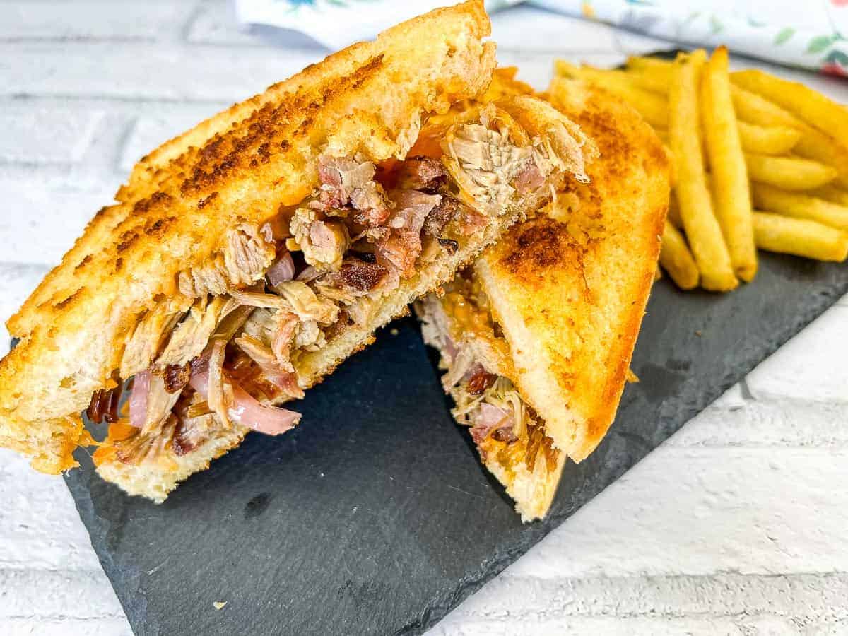 A pulled pork grilled cheese sandwich on a slate plate.