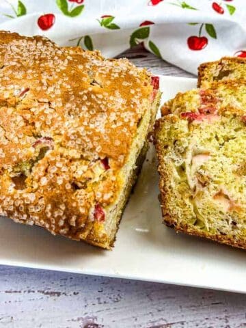 A loaf of Rhubarb Bread with a few slices on a white plate.
