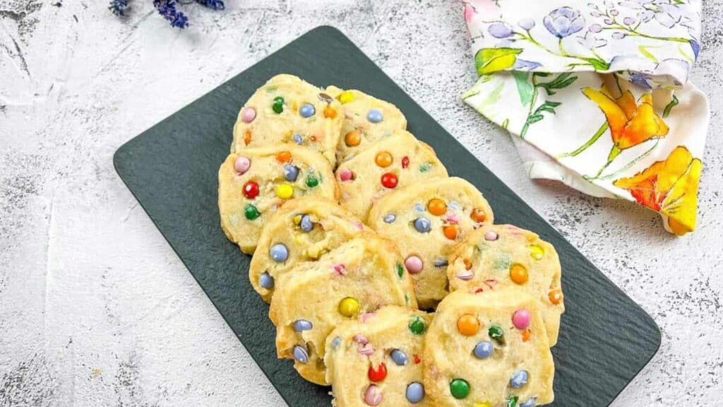 Shortbread M&M cookies on a black slate.