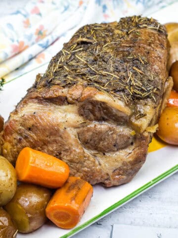 A plate with a Slow Cooker Herb-Crusted Pork Roast and roasted vegetables.