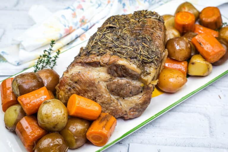 A Slow Cooker Herb-Crusted Pork Roast and roasted vegetables on a plate.