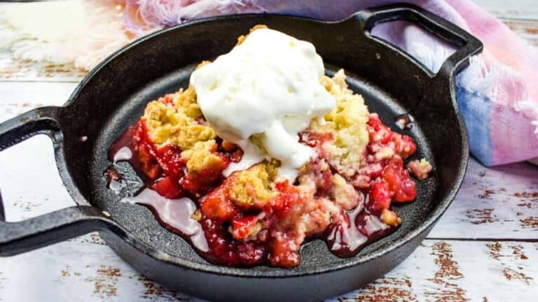 Strawberry Rhubarb Crumble in cast iron with vanilla ice cream on top.