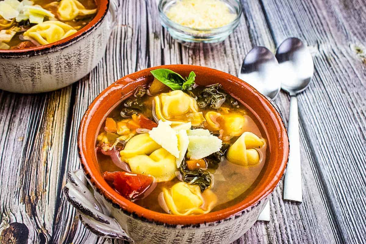 Tortellini soup with kale and chicken in a bowl.