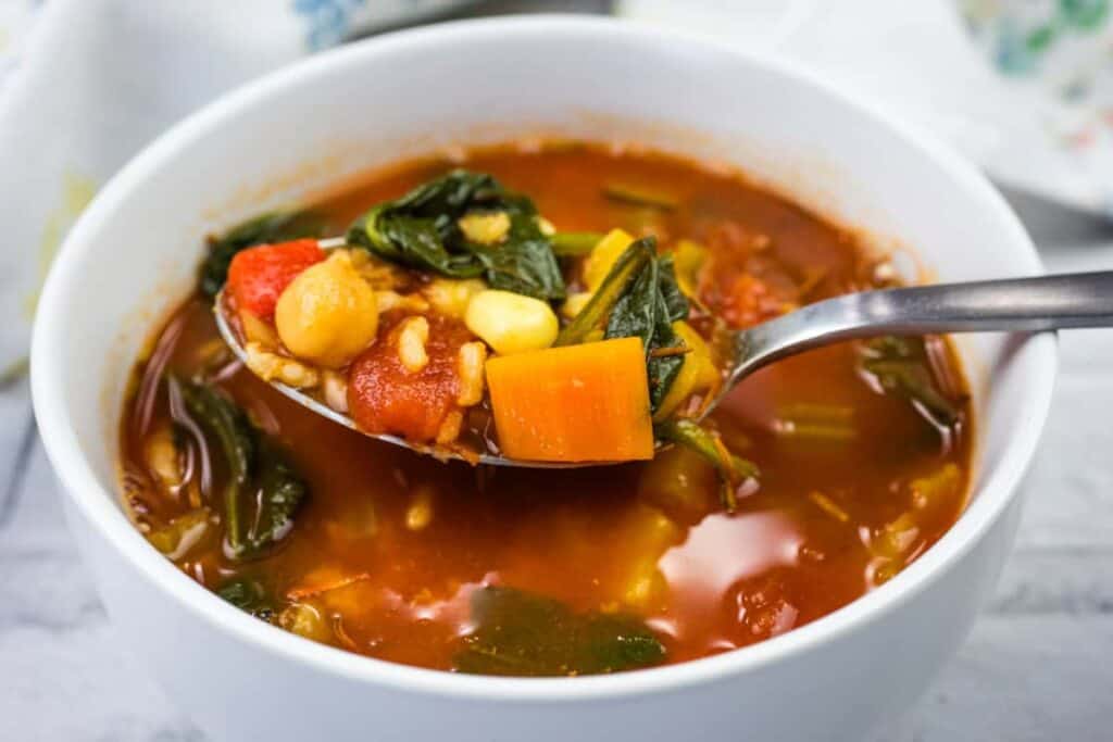 A spoonful of Copycat Panera Bread&rsquo;s 10 Vegetable soup from a white bowl.