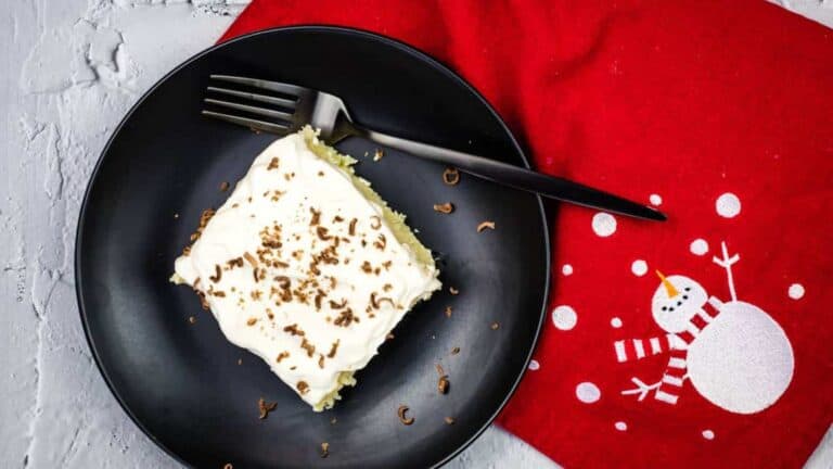 A piece of eggnog tres leches cake on a black plate with a fork.