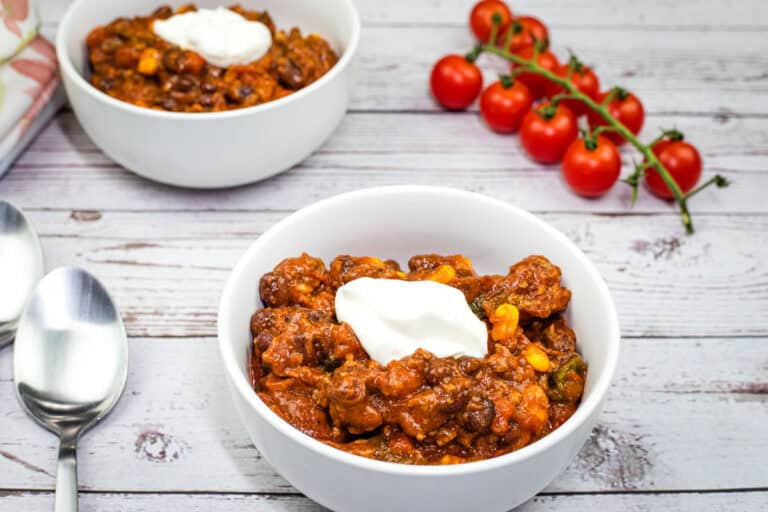 Two bowls of Slow Cooker Southwestern Chili topped with sour cream.