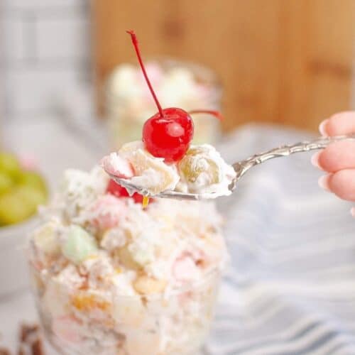 Bowl of ambrosia salad with mixed fruit and marshmallows.