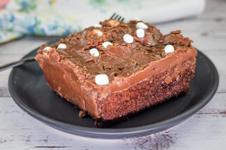 A square of coca-cola cake on a black plate.