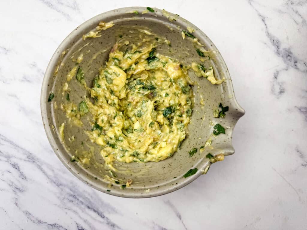A mixture of salted butter, Worcestershire sauce, shallots, garlic parsley, lemon juice, and ground black pepper in a bowl.