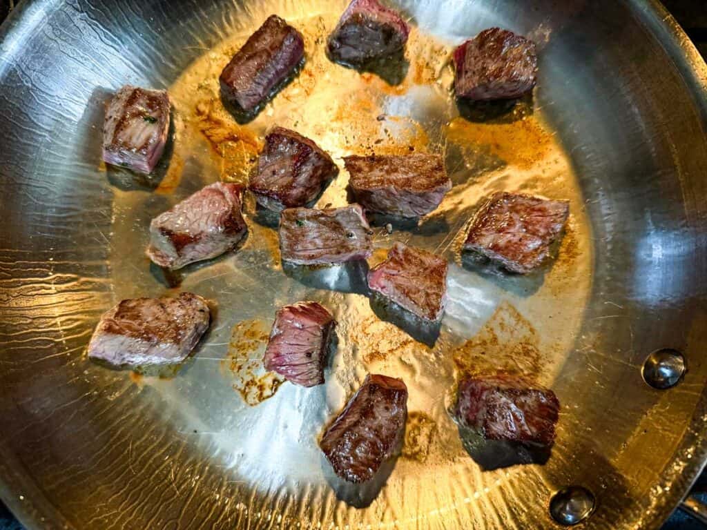 Cooking the steak bites in a skillet.