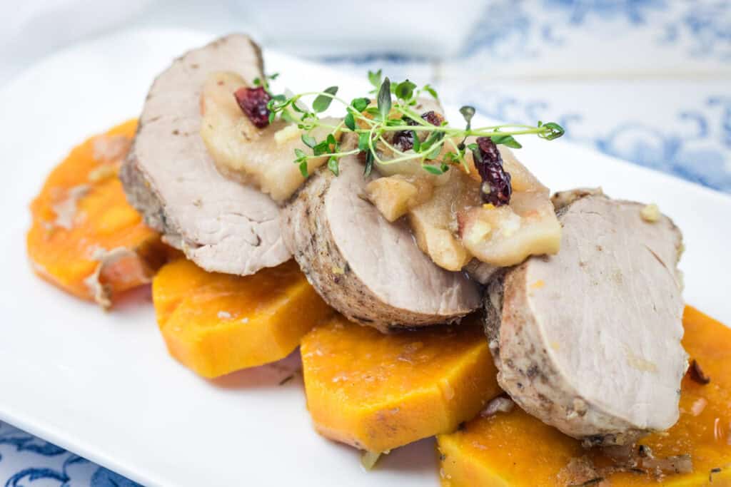 A serving of Slow Cooker Pork Tenderloin with Sweet Potatoes & Apples in a white platter.
