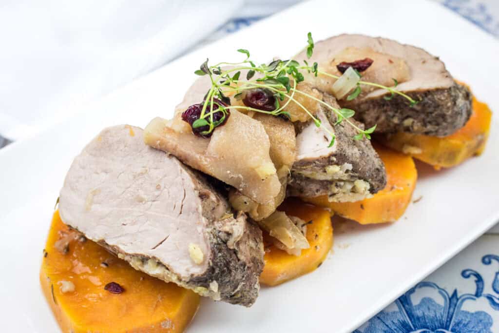 A serving of Slow Cooker Pork Tenderloin with Sweet Potatoes & Apples on a white plate.